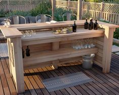 an outdoor bar with wine glasses and bottles on the top shelf, sitting on a deck