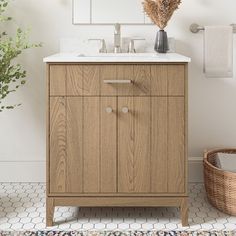 a bathroom vanity with two mirrors above it and a basket on the floor next to it