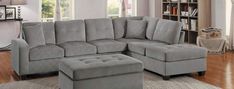 a living room with a gray sectional couch and footstool in front of a bookcase