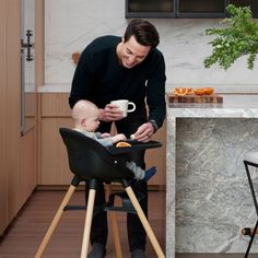 a man feeding a baby in a high chair