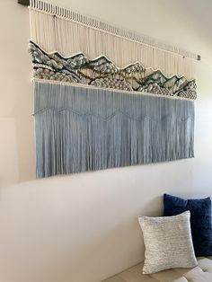 the wall hanging is decorated with fringes and beads on it's sides, along with a blue pillow