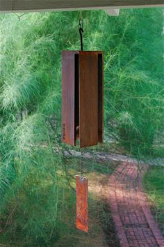 a wooden wind chime hanging from the side of a window next to a brick walkway