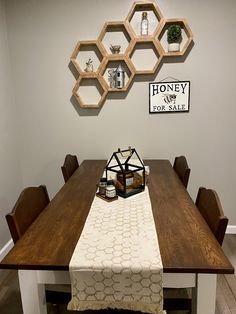 a wooden table topped with a white and brown table cloth next to shelves filled with honeycombs