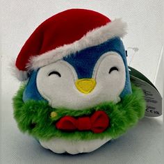 a stuffed animal with a santa hat and green fur around it's neck, sitting on a white surface