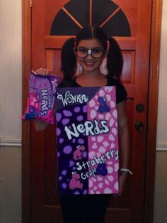 a girl holding up a sign that says nerds and strawberry shortcakes in front of a door