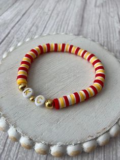 a red, yellow and white beaded bracelet on a wooden surface with beads around it