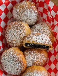 powdered sugar covered pastries in a red and white basket on a wooden table