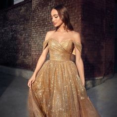 The Elegant Dress That Is Perfect For A Formal Event Is Made Of Delicate Glitter Tulle, Which Makes The Skirt Voluminous Creating A Light Image, While The Off Shoulder Neckline Will Complement The Image With Exquisite Jewelry. Fabric: Tulle Length: Tea Length Colour: Gold Neckline: Off Shoulder Silhouette: A-Line Sleeve: Sleeveless Back: Zipper Embellishments: Glitter Occasion: Romantic Date/Evening/Dinner, Wedding/Bridesmaid, Graduation, Fashion Show, Visiting Theater/Museum/Restaurant, Banquet Evening Dresses Elegant Off Shoulder, Gold Midi Dress Bridesmaid, Sparkly Gold Gown, Gold And Purple Wedding Dress, Gold Masquerade Dress, Gold Prom Looks, Gold Sparkle Prom Dress, Gold Dress With Sleeves, Ball Gown Dresses Elegant