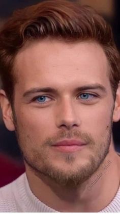 a close up of a person with a beard and blue eyes looking at the camera