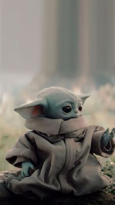 a baby yoda doll sitting in the grass