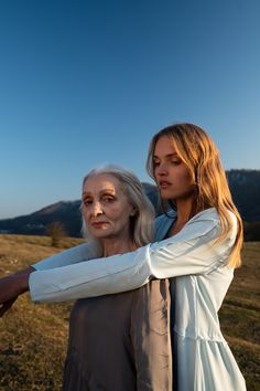 two women standing next to each other in a field