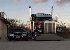 a large semi truck parked next to a black car