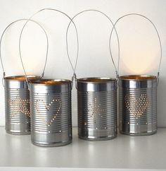 three tin can lights sitting on top of a white shelf next to two empty cans