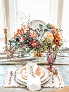 an elegant table setting with orange and pink flowers