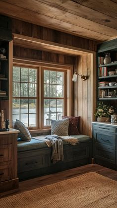 a window seat in the corner of a room with bookshelves and cabinets on either side