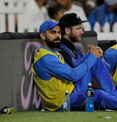 two men sitting next to each other on top of a field