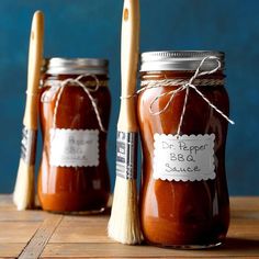 two jars filled with red sauce sitting on top of a wooden table