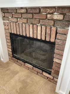 a brick fireplace with the door open and tile flooring on it's sides