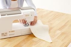 a woman is using a sewing machine to sew something on a piece of paper