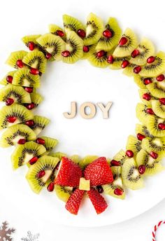 a white plate topped with kiwis and strawberries next to a candy cane