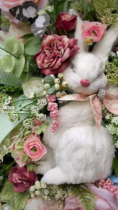 a white stuffed rabbit surrounded by flowers and greenery