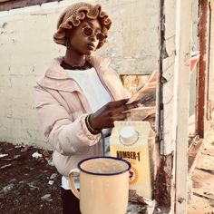 a woman standing next to a wall with a cup of coffee in front of her