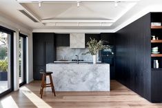 a kitchen with black cabinets and white marble countertops is seen in this modern home