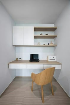 a chair sitting in front of a desk with a laptop on it and shelves above