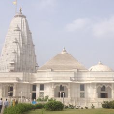 people are walking around in front of a white building with two spires on each side