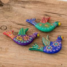 three colorful birds sitting on top of a wooden table