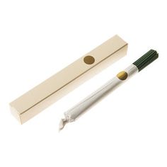 a white and green toothbrush sitting next to a cardboard box on a white surface