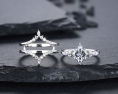 three different types of engagement rings on a rock with rocks in the foreground and black background