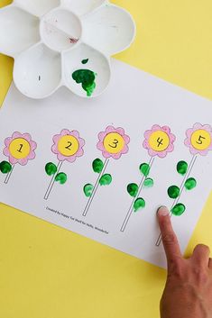 a child's hand pointing at the flowers on a paper sheet with letters and numbers