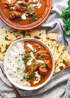 a bowl of chicken tikka with rice and pita bread on the side next to it