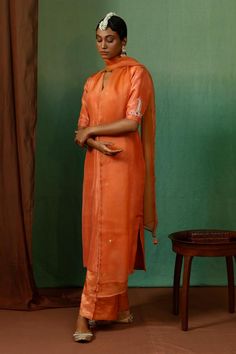 Rust orange silk kurta with placement vintage motif, contrast thread, zari, bead and sequin embroidered half sleeves. Paired with tissue stripe pattern straight pant and organza embroidered dupatta.
Components: 3
Pattern: Embroidered
Type Of Work: Sequin, Zari, Thread and Bead Work
Neckline: V Neck
Sleeve Type: Half Sleeves
Fabric: Kurta: Silk, Pant: Tissue, Dupatta: Organza
Color: Orange
Other Details: 
Tasselled dupatta edges
Beaded hem details
Lace work dupatta border
Side slits on kurta
Occa Tissue Dupatta, Dupatta Border, Silk Pant, Kurta Set For Women, Indian Dresses Traditional, Silk Kurta, Embroidered Dupatta, Rust Orange, Kurta Set