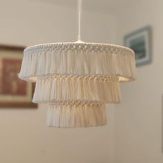 a white chandelier hanging from a ceiling in a room with pictures on the wall