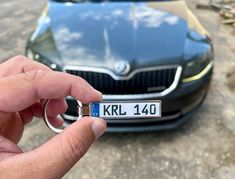 a person holding a keychain in front of a car