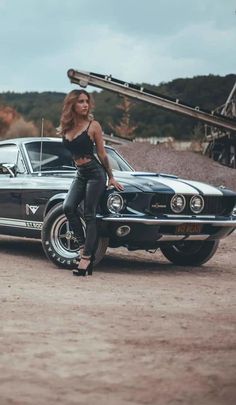 a woman standing next to a car in the dirt