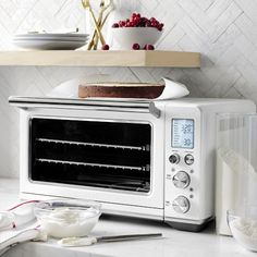 a white toaster oven sitting on top of a counter next to bowls and plates