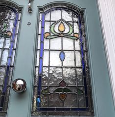 two stained glass windows on the side of a blue door with chrome handles and knobs