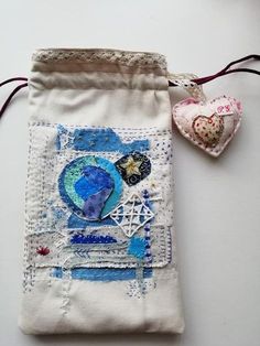 a small bag with some fabric on it and two hearts hanging off the side of it