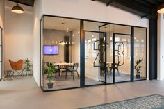 an office with glass walls and black framed sliding doors that lead into the dining area