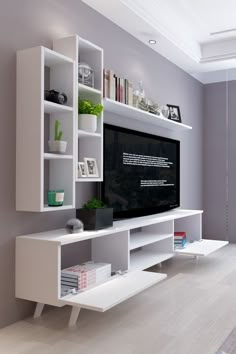 a white entertainment center with bookshelves and a flat screen tv mounted on the wall