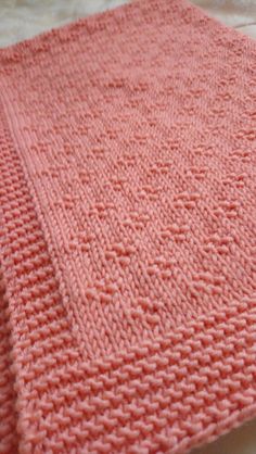 an orange knitted blanket laying on top of a bed