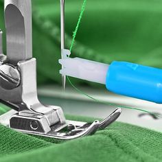 the sewing needle is being used to sew something green and blue in this image