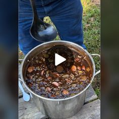 a large pot filled with lots of food on top of a wooden table next to a spoon