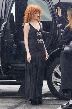 two women standing next to each other in front of a black vehicle with the door open