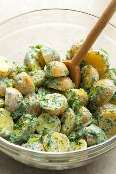 a glass bowl filled with potato salad and a wooden spoon