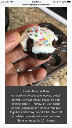 a person holding a chocolate cookie with white frosting and sprinkles on it