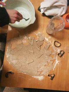 a person is making cookies on a wooden table with letters and numbers in the shape of hearts